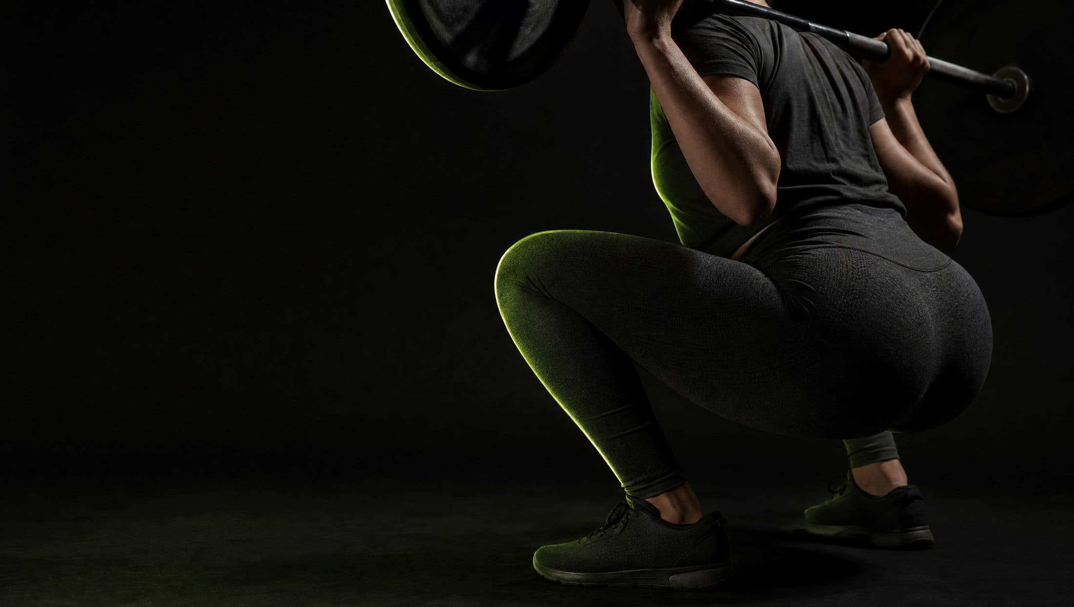 An athlete held at the bottom of a loaded back squat, lit so the fabric tension across the leg is visible